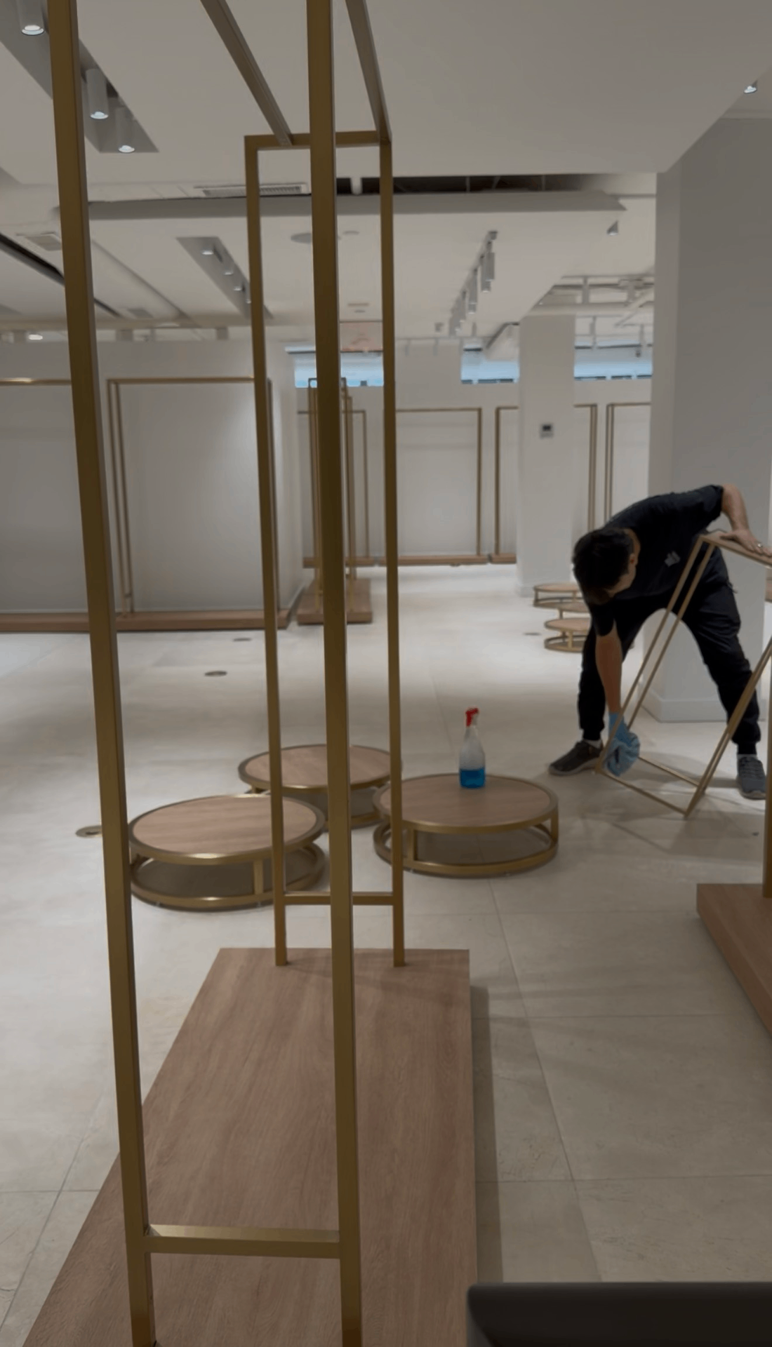 Premium Cleaning technician wiping down brass and wood fixtures inside Pernia's Pop-Up Shop showroom
