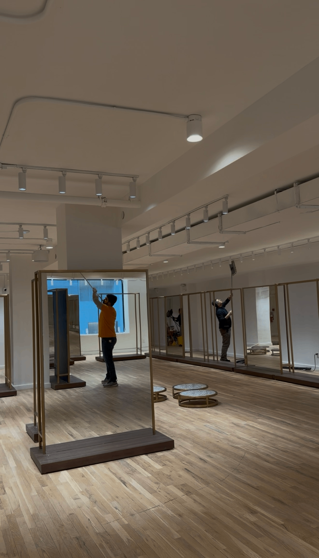 Premium Cleaning team detailing high ceilings and mirrors inside the Pernia's Pop-Up Shop showroom