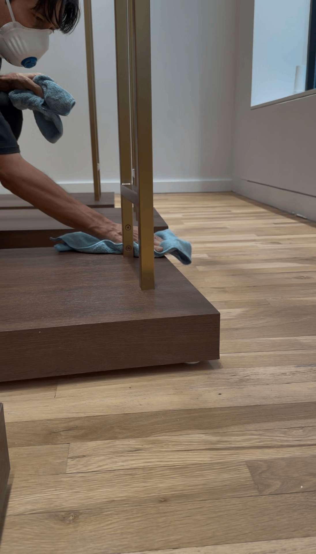 Premium Cleaning technician detailing wood platforms and brass fixtures on the showroom floor